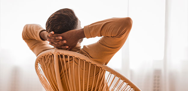 man relaxing with hands behind head