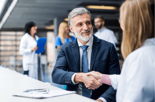 Male and female medical professionals shake hands, representing strategic partnerships and collaboration in clinical development