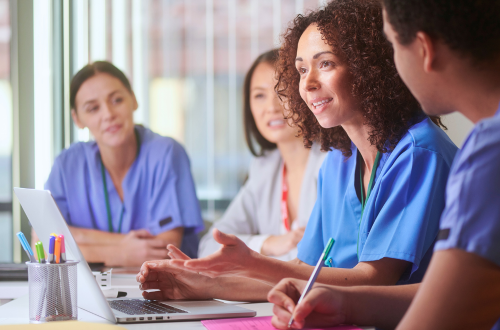 A group of clinicians at a table with a laptop and paperwork, representing technology enhancing oncology clinical trials