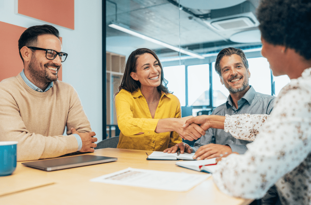 A group of business people shaking hands in an office during a CRO meeting.