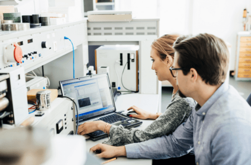 Two people from Contract Research Organizations working on a computer in a laboratory.